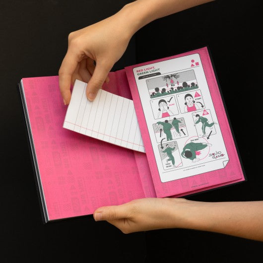 Página interna do caderno Squid Game com padrão de grade e bolso rosa.