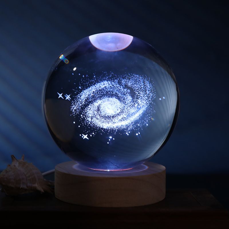 Bola de cristal com galáxia e luz LED multicolor, 10 cm de diâmetro, sobre base de madeira