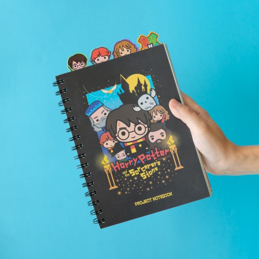 Pessoa a segurar o caderno Harry Potter com capa preta e personagens da saga.