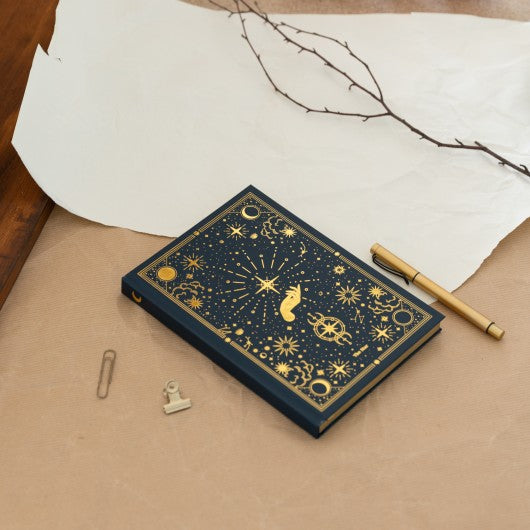 Caderno premium com detalhes astronomicos dourados ao lado de uma esferografica e acessorios de escritorio.