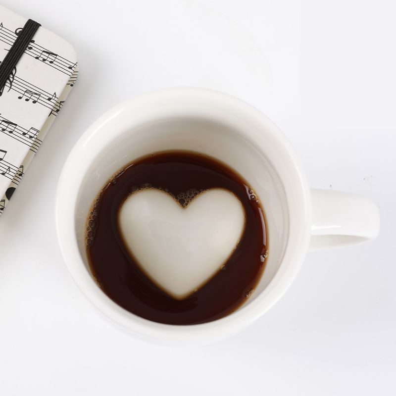 Caneca 3D com café a revelar um coração em relevo no fundo.