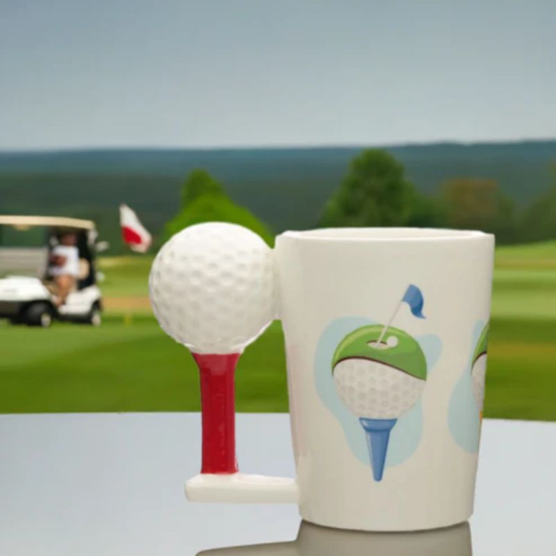 Caneca com design de golfe colocada numa mesa com campo de golfe ao fundo.