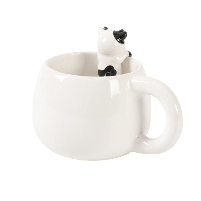 Vista lateral da caneca branca com figura de vaquinha no interior, voltada para o lado.