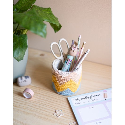 Caneta Pusheen multicolor com topo 3D exposta em cesto com outros materiais.