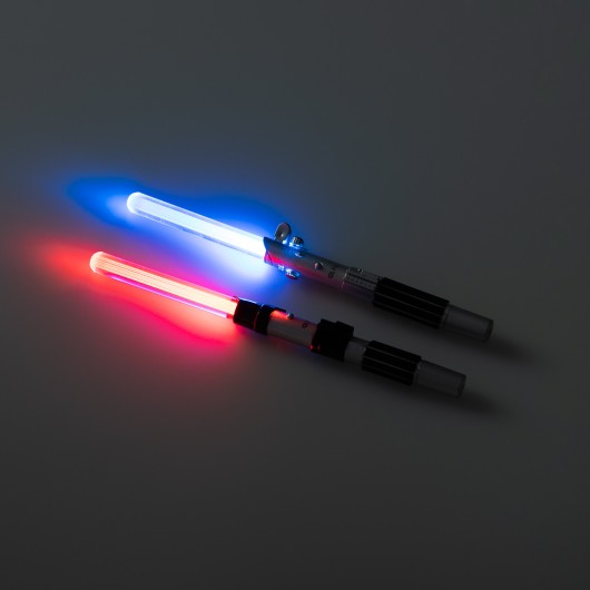 Canetas sabres de luz Star Wars com luzes LED azul e vermelha acesas, destacando o brilho em ambiente escuro.
