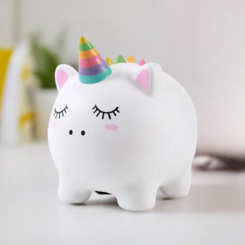Mealheiro de unicórnio decorativo pousado numa secretária com fundo desfocado.
