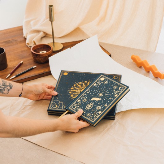 Conjunto de caderno A5 e esferografica dourada exibidos numa cena de escritorio sofisticada.