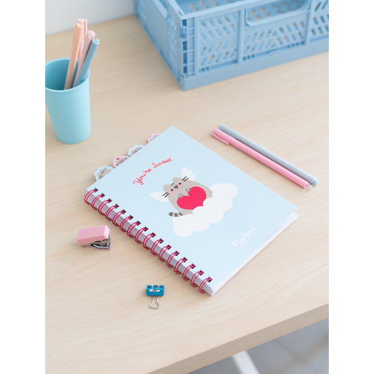 Caderno Pusheen A5 decorado com materiais escolares, ideal para organização e estudo.