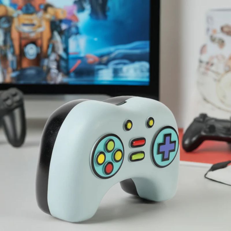 mealheiro para crianças e jovens em forma de comando de consola de jogos,  pousado numa secretaria com monitor e video jogo