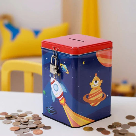 um mealheiro retangular em metal com cadeado e desenhos infantis espaciais rodeado por moedas