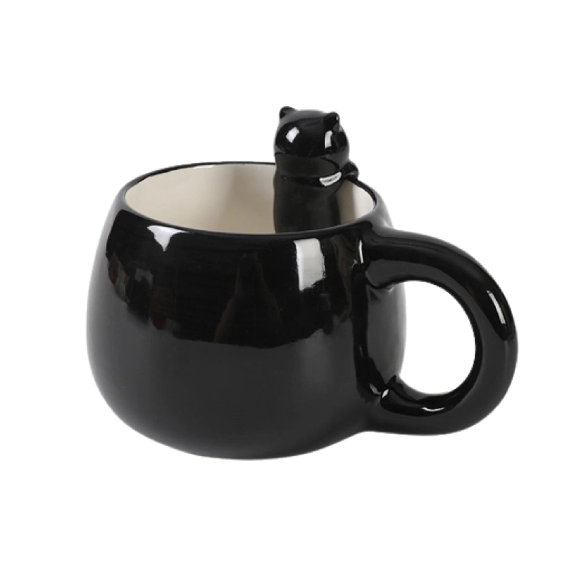 Caneca preta com figura de gato preto espreitando sobre a borda, vista de lado.