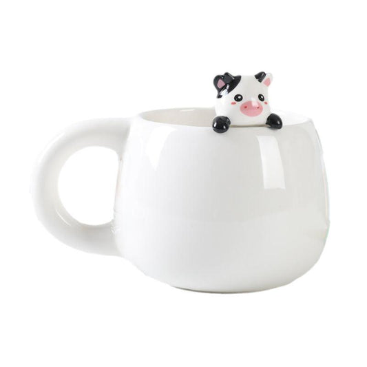 Caneca branca com figura de vaquinha preta e branca a espreitar do interior.