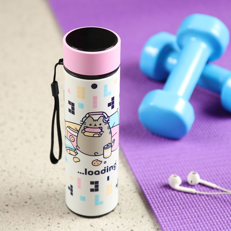 Garrafa térmica Pusheen com tampa rosa e ilustrações coloridas em um fundo de ginásio com halteres e tapete de yoga.